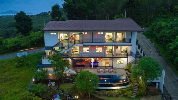 Une maison à deux étages avec un balcon, une piscine et un jardin.
