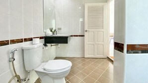 Een badkamer met toilet, wastafel, spiegel en een deur.