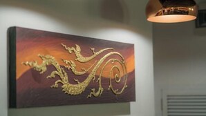 Een muur met een lijstwerk waarin een ontwerp van een draak staat.