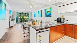 A modern kitchen with a dishwasher, wooden cabinets, and a granite countertop. - Chevron Renaissance Garden View (Surfers Paradise)