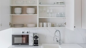 Une cuisine moderne avec des meubles blancs, un four encastré et un évier en acier inoxydable.