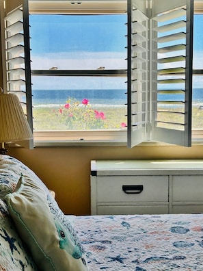 A bedroom with a bed, a bedside table, a lamp, and a window with white blinds.
