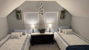 Un dormitorio con dos camas, una mesita de noche, un espejo y dos ventanas con persianas.