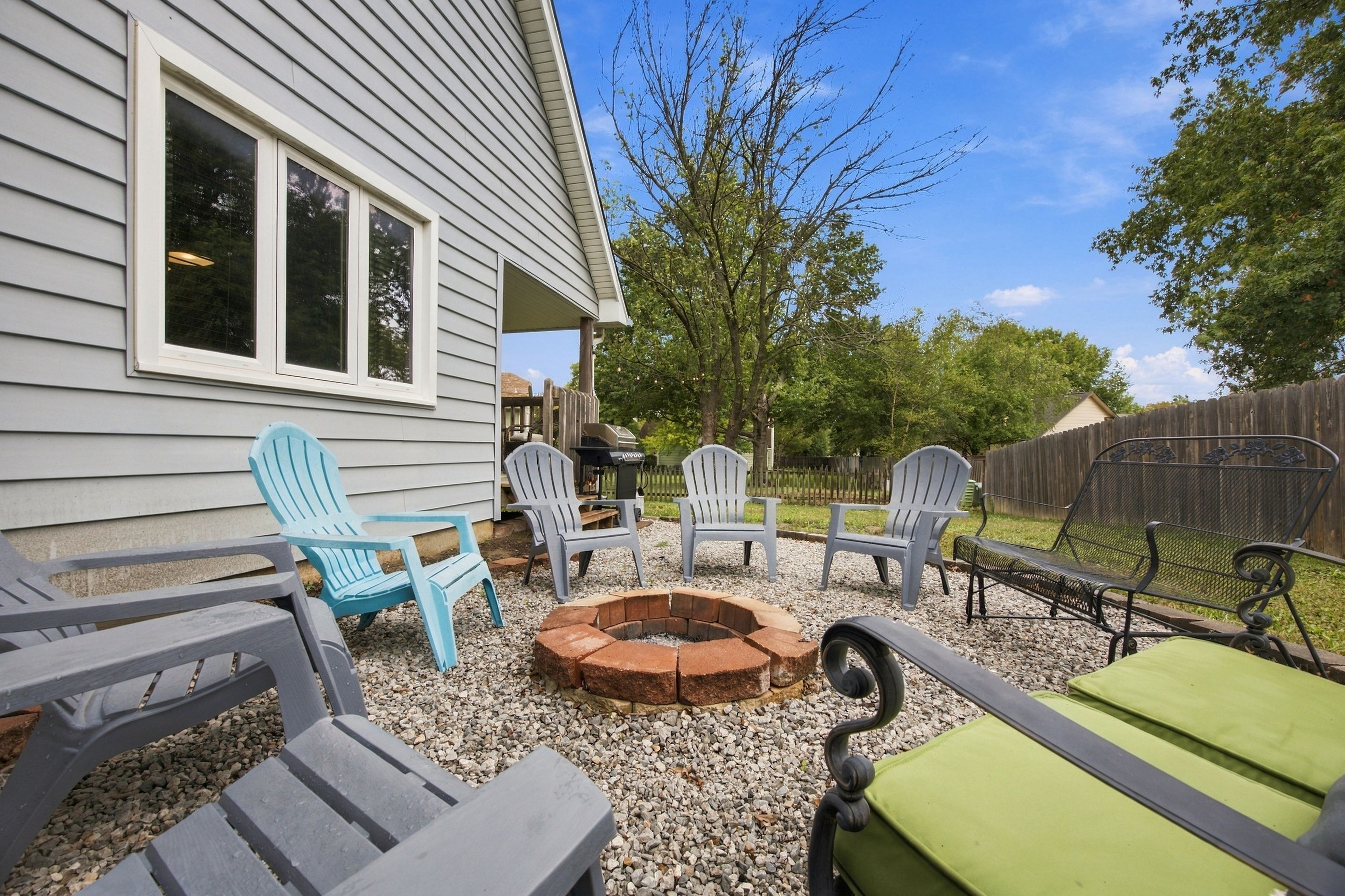 Une terrasse avec des fauteuils Adirondack, un foyer et un espace barbecue.