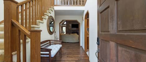 Un escalier en bois avec un banc rembourré, une porte et une vue sur une pièce dotée d’une cheminée.