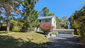 A two-story house with a front porch, a garage, and a well-maintained lawn. - 4-bedroom house in Ithaca, 5 min from Cornell Graduation (Ithaca)