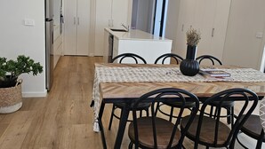 Una cocina moderna con armarios blancos, una mesa de comedor de madera con sillas negras y una planta en maceta.