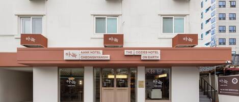 Un hotel con due ingressi, ognuno con la scritta 'AANK HOTEL' e 'THE COZIES HOTEL ON EARTH'.