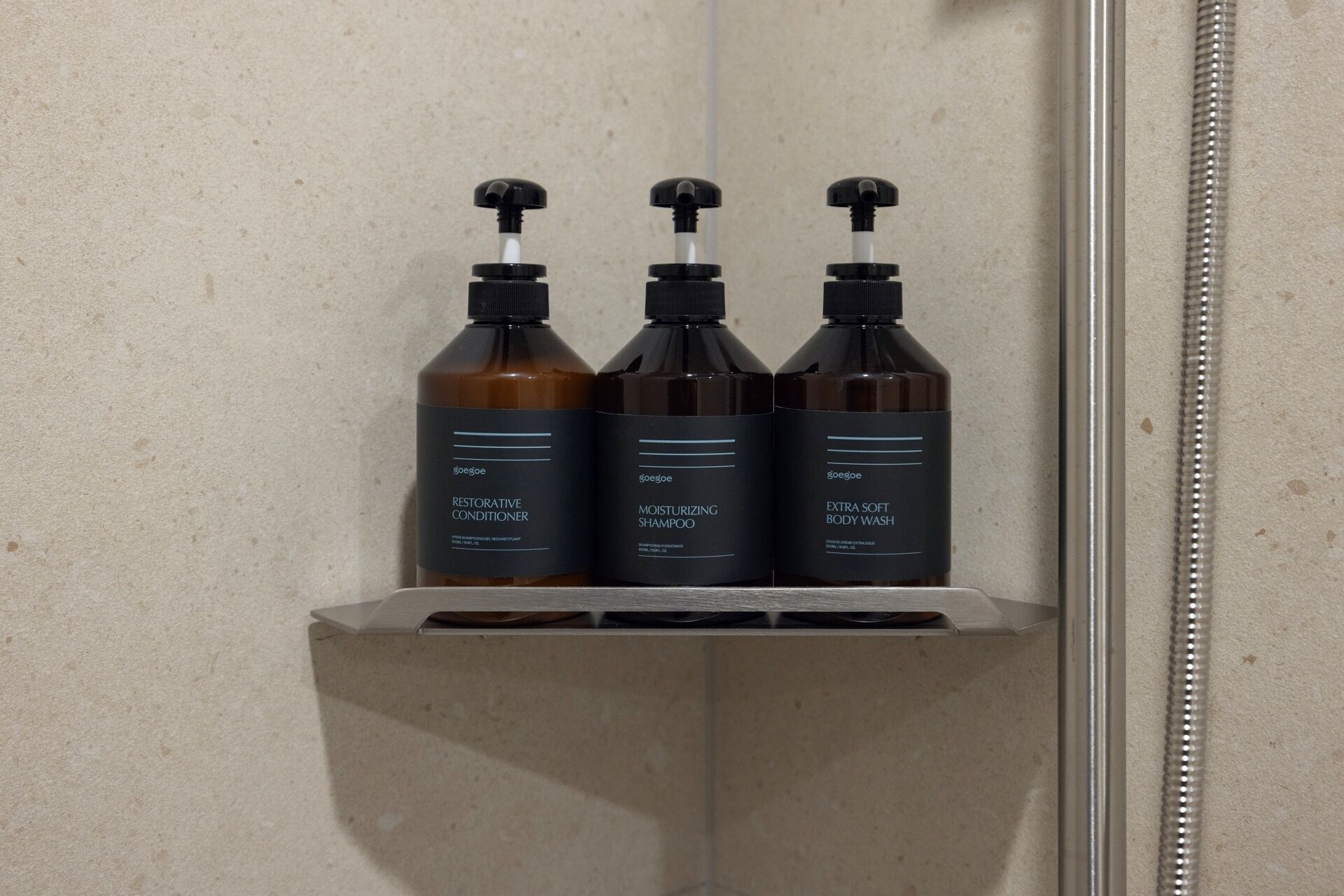 A bathroom shelf with three bottles of hair care products.