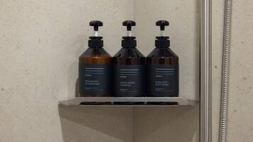 A bathroom shelf with three bottles of hair care products.