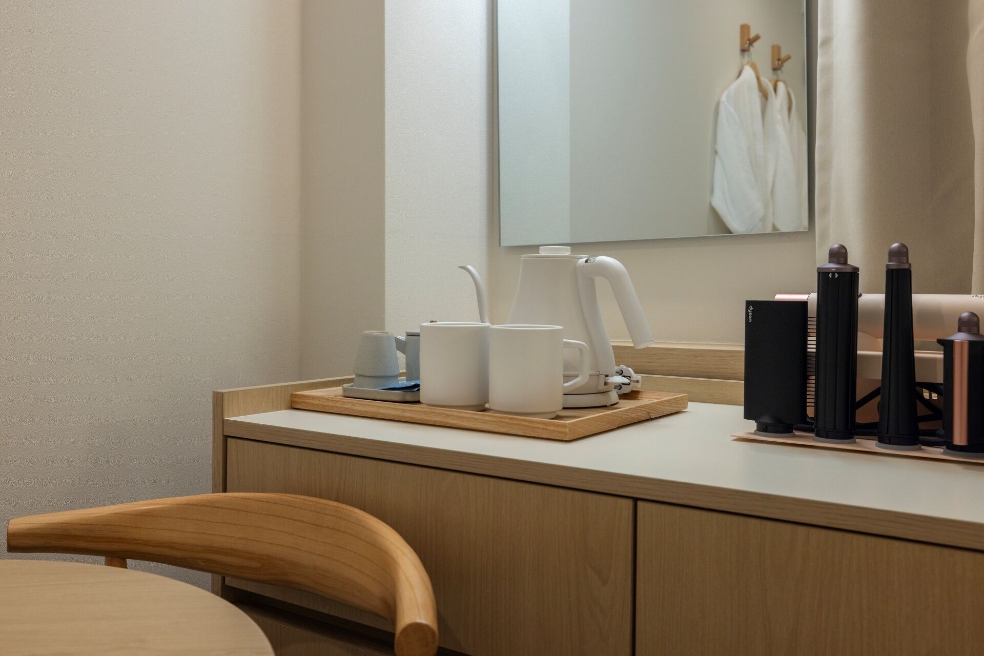 Ett modernt hotellrum med ett skrivbord i trä, en kaffebryggare och en svart högtalare.