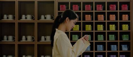 A woman standing in front of a wall with multiple shelves containing various tea products.