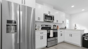Una cocina moderna con armarios blancos, electrodomésticos de acero inoxidable y un horno empotrado.