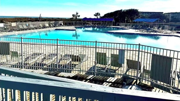 A pool area with a fenced deck, lounge chairs, and a clear view of the surrounding landscape.