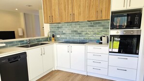 A modern kitchen with white cabinets, a dishwasher, a microwave, and an oven.