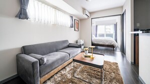 Une pièce moderne et bien éclairée, avec un canapé gris, une petite table basse en bois et un tapis moelleux.
