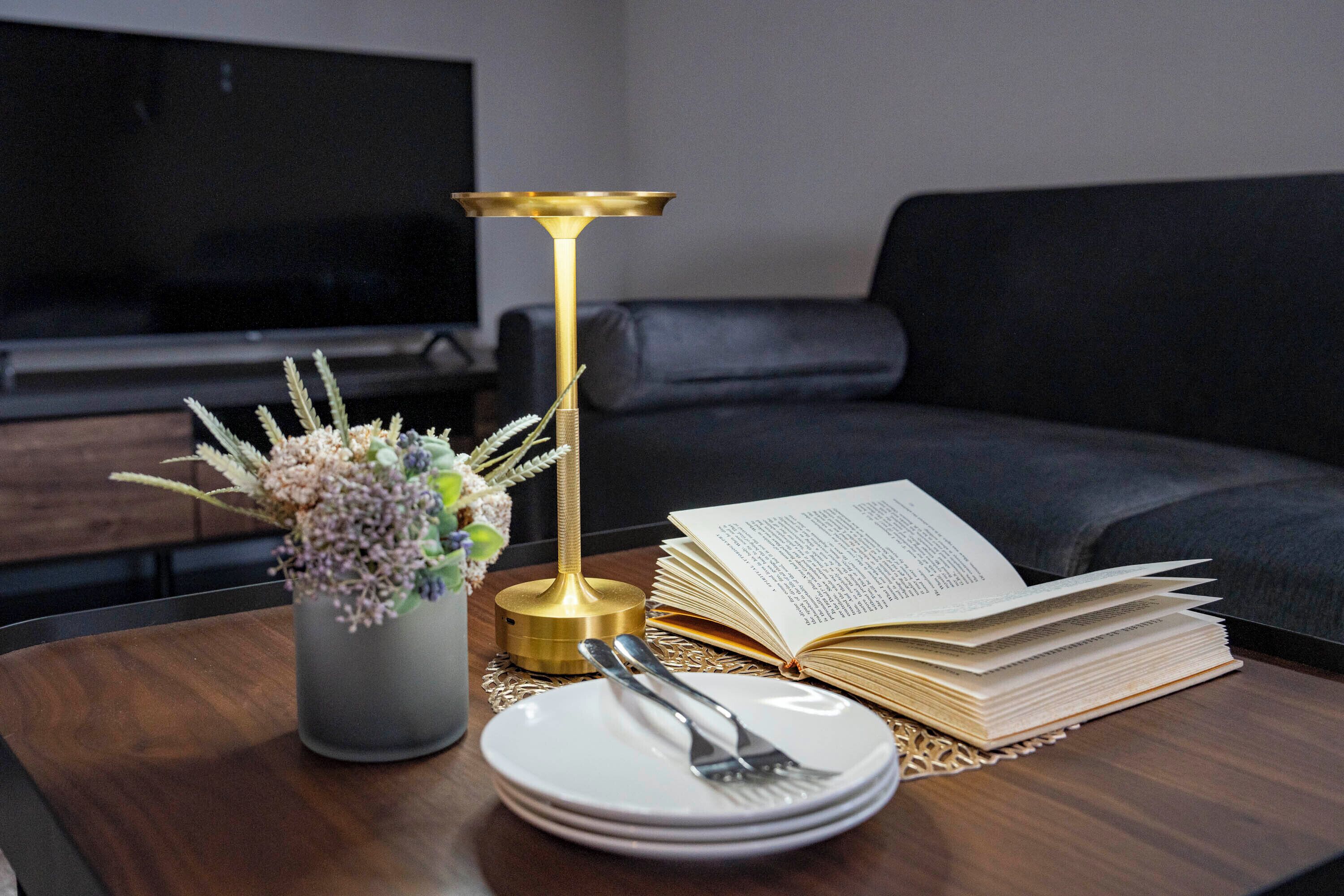 A dining table with a book, a vase of flowers, and a candle.