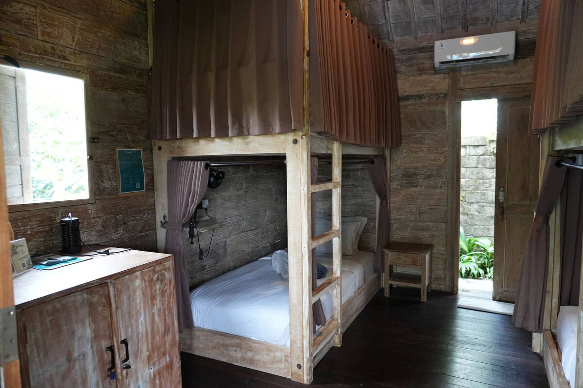 Una stanza rustica in legno con un letto a castello, una scrivania e un piccolo tavolo.