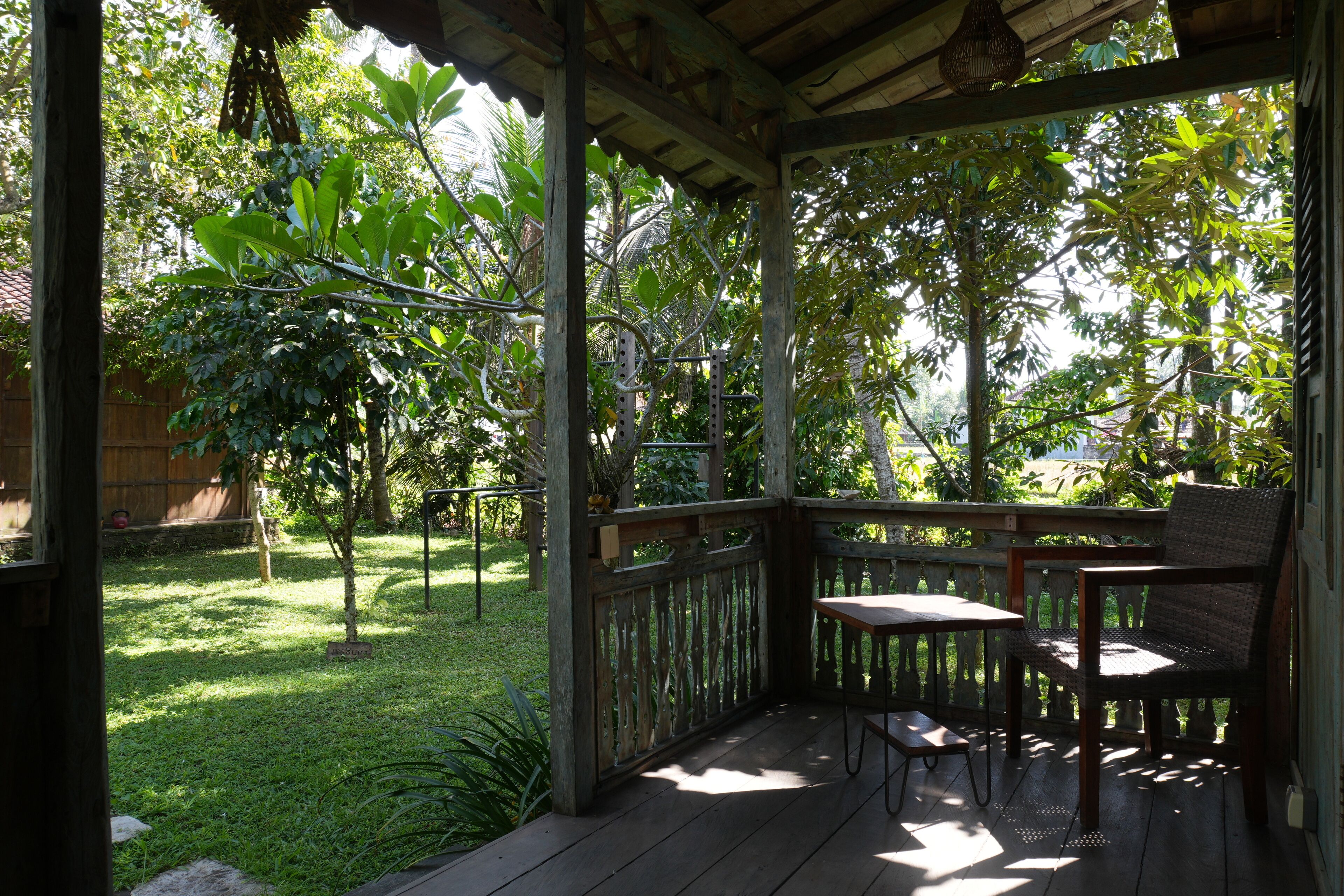 Une terrasse en bois avec une table et des chaises, entourée d’une végétation luxuriante et d’arbres.
