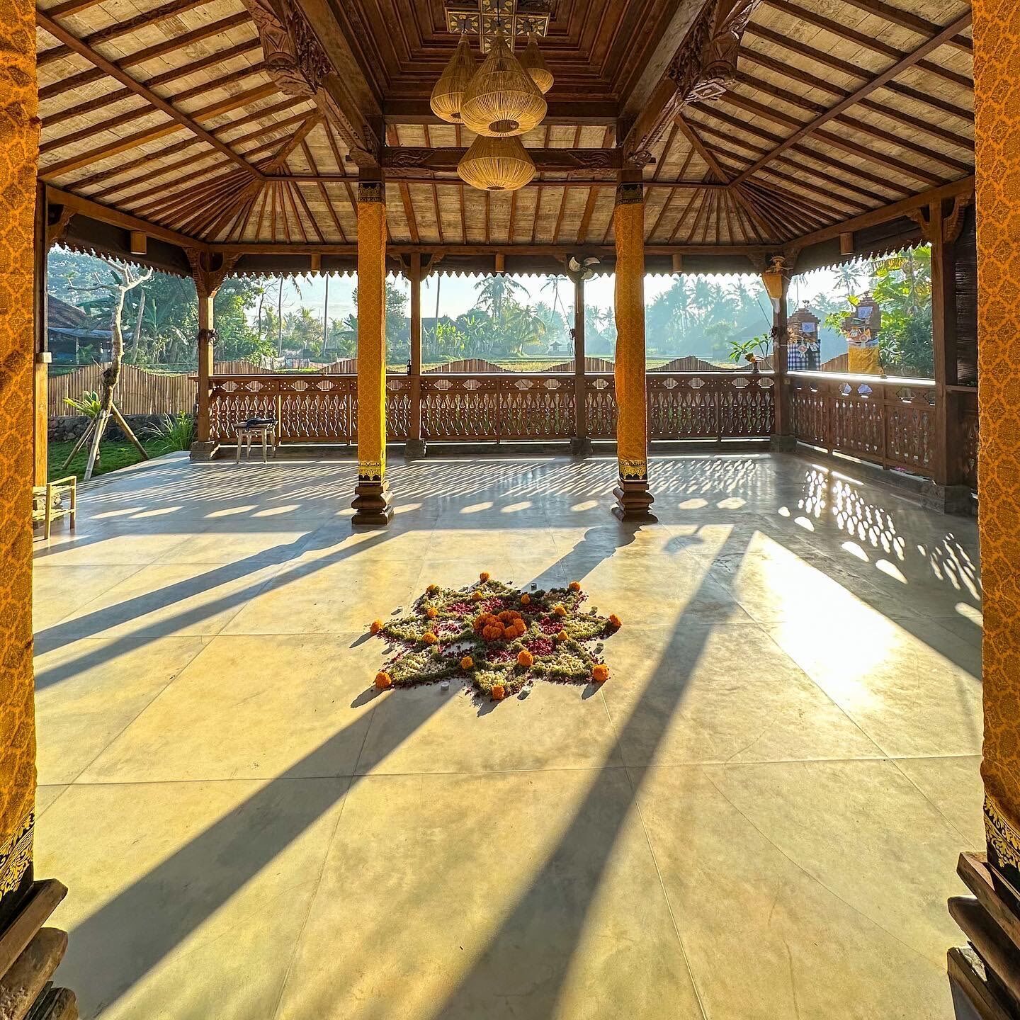 A covered outdoor area with a patterned floor, a decorative floral arrangement, and a view of the surrounding landscape.