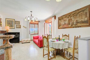 Un coin repas avec une table dressée pour quatre personnes, un canapé rouge et un grand tableau accroché au mur.