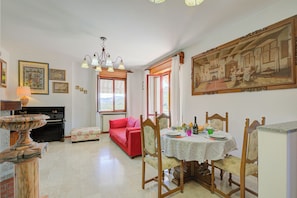 A dining area with a table set for four, a red sofa, and a large painting on the wall.