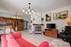 A living room with a red sofa, a fireplace, a television, and a bookshelf. - A Due Passi Dal Bosco: Hillside Apartment with Garden&BBQ, Laveno Mombello, Italy (Laveno Mombello)