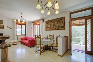 Un coin repas avec une table dressée pour deux personnes, un canapé rouge et un lustre.