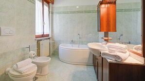 A bathroom with a toilet, bidet, bathtub, and a sink with a mirror above it. - A Due Passi Dal Bosco: Hillside Apartment with Garden&BBQ, Laveno Mombello, Italy (Laveno Mombello)