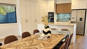 A modern kitchen with white cabinets, a built-in microwave, and a stainless steel refrigerator.