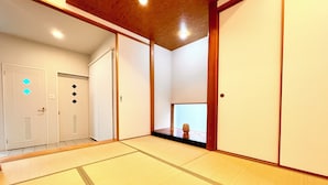 Um quarto japonês tradicional com piso de tatame, portas deslizantes e uma pequena mesa com um vaso.