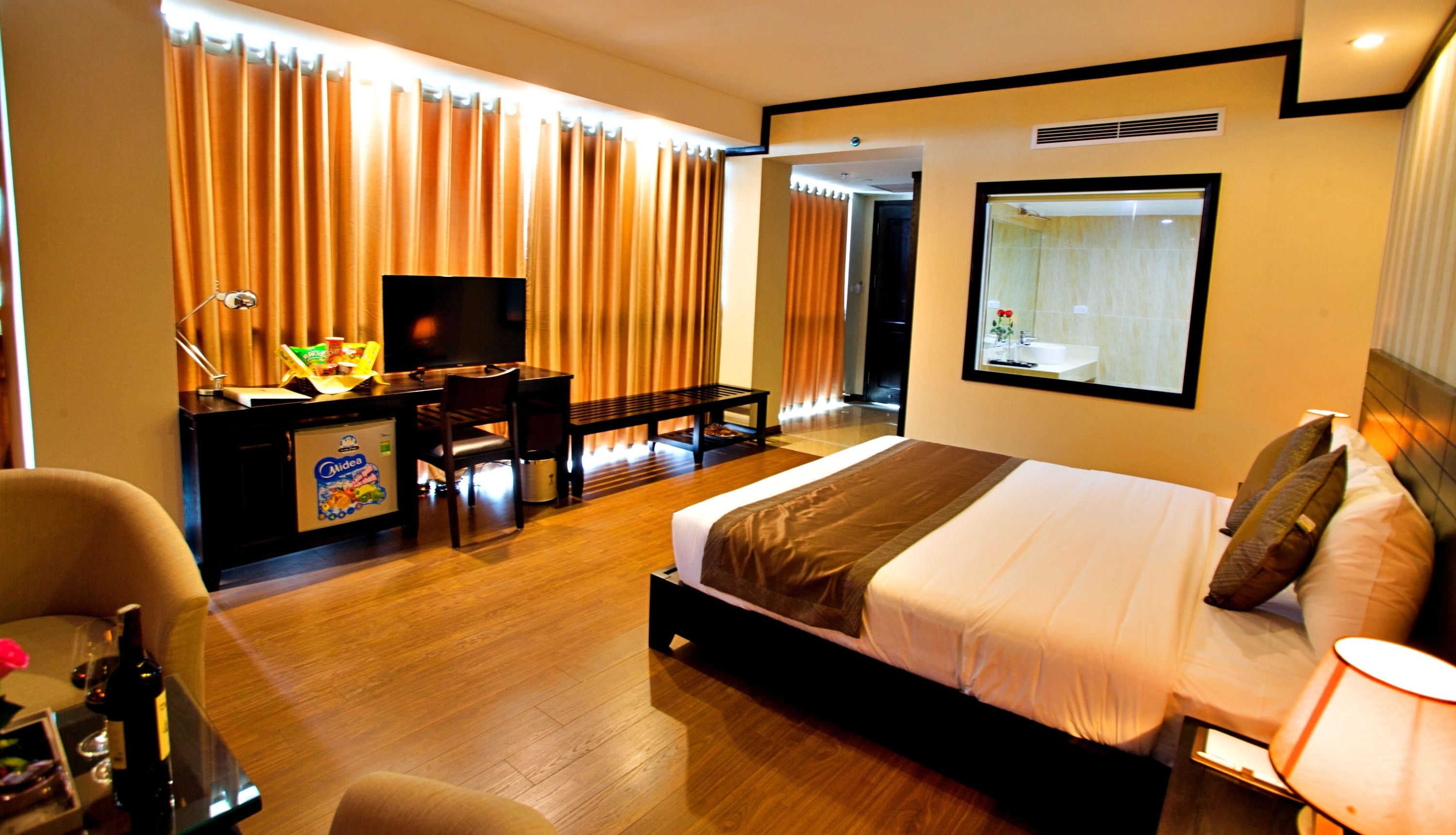 Une chambre d’hôtel équipée d’un lit, d’un bureau, d’une chaise, d’une télévision et de rideaux.
