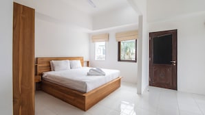 Quarto com cama de madeira, roupa de cama branca, ventoinha no teto e vista para o exterior através de uma janela com persianas.