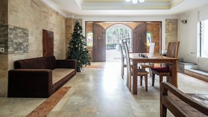 Um hall amplo com piso de mármore, mesa de centro de madeira, uma árvore de Natal e um jogo de xadrez.