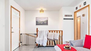 A hotel room with a bed, a sofa, a staircase, and a painting on the wall. - Quaint Swiss Chalet • Steps from Main St- Sleeps 5 (Midway)
