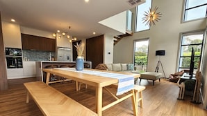 Une cuisine moderne avec des meubles en bois, un coin repas avec une table et un banc en bois, et un salon avec un canapé et un téléviseur.