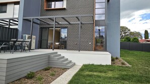 Une maison moderne avec une façade en briques, de grandes fenêtres et un patio couvert.