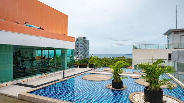 A rooftop pool with a blue mosaic floor, surrounded by potted plants and a glass balustrade. - C-View Boutique (Pattaya)