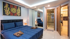 A modern bedroom with a large bed, a glass shower, and a wooden door. - C-View Boutique (Pattaya)