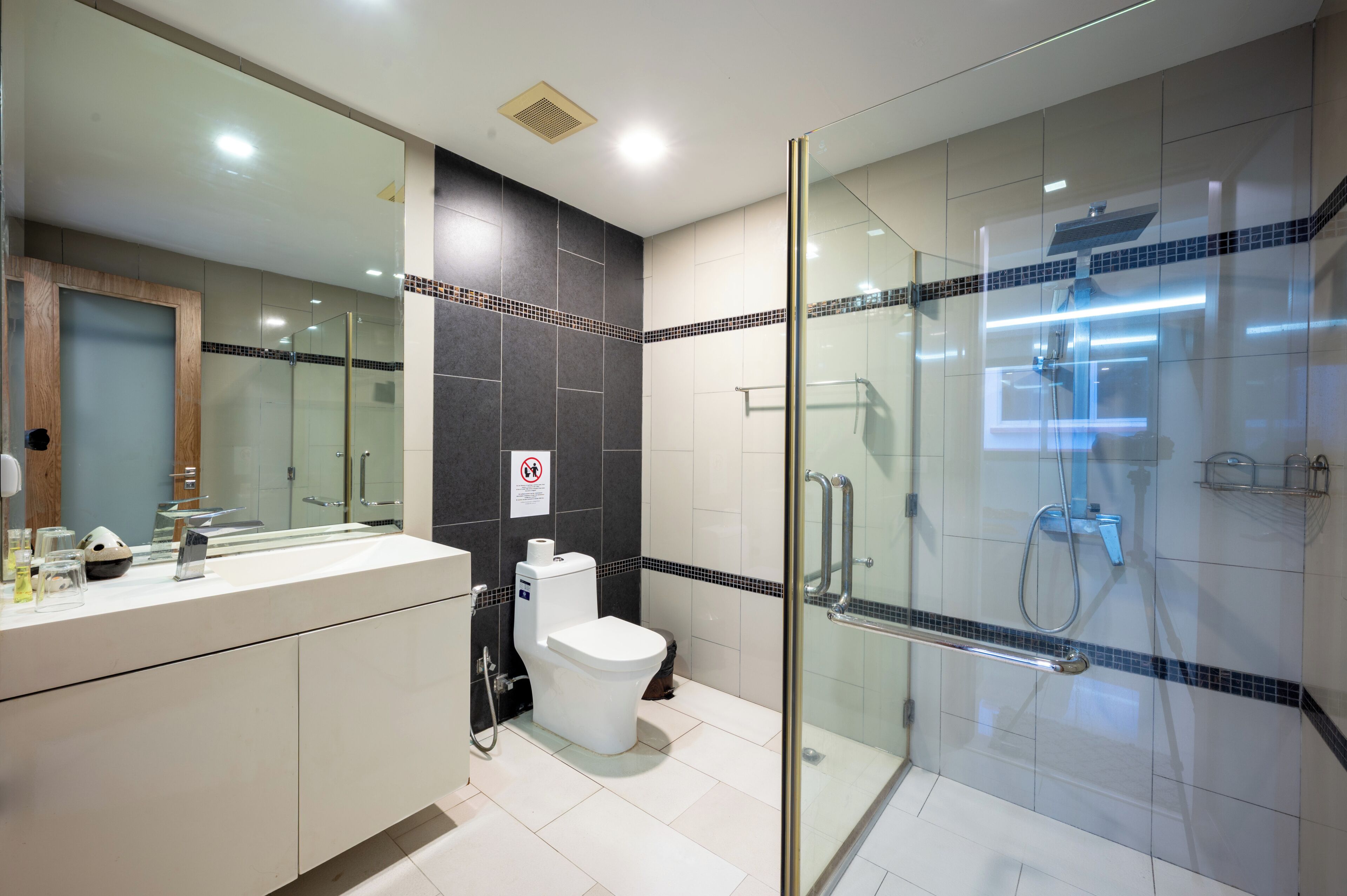 Un baño moderno con ducha de vidrio, inodoro y tocador con espejo.