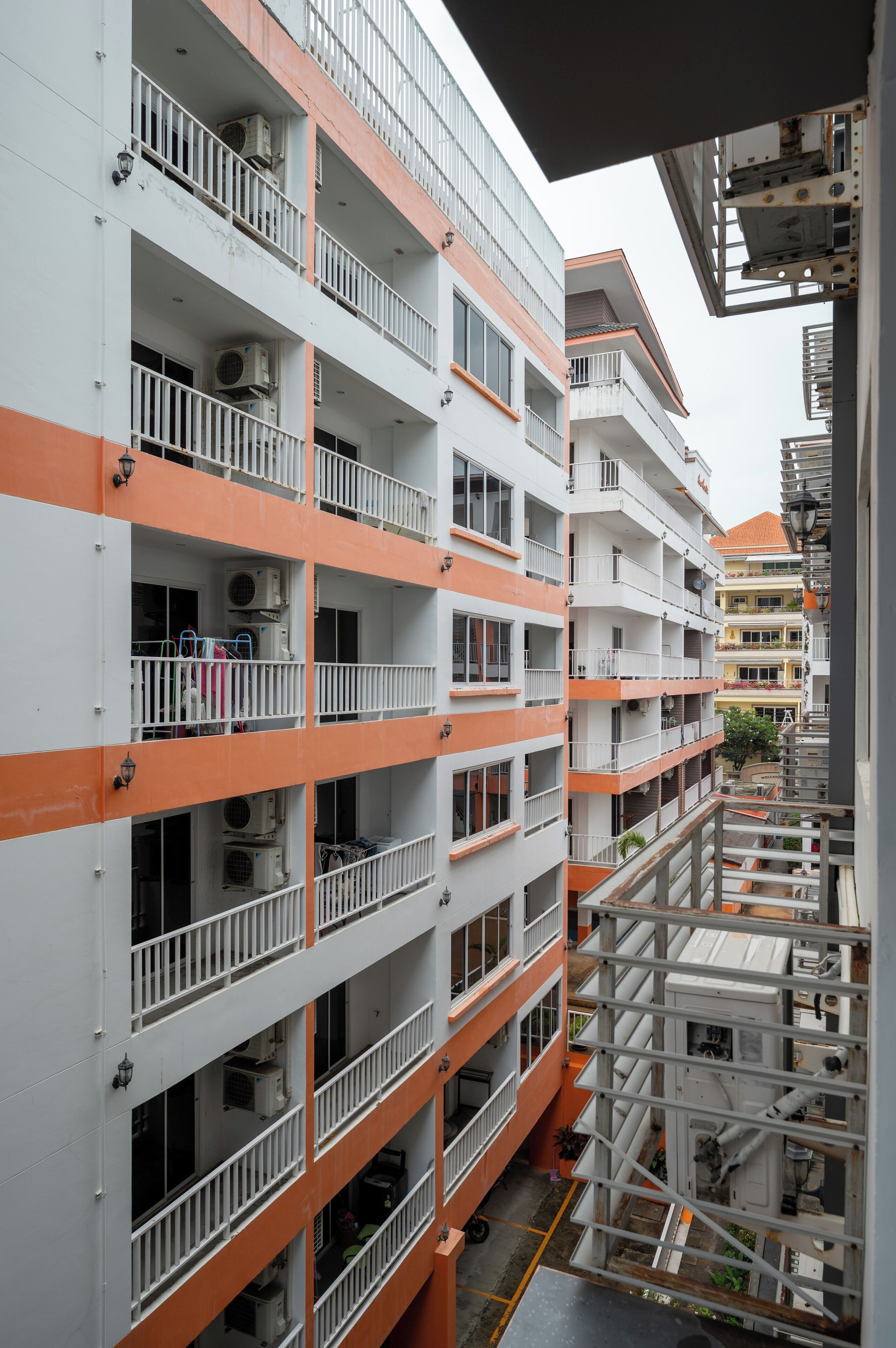 A multi-story residential building with balconies, air conditioning units, and a central courtyard.