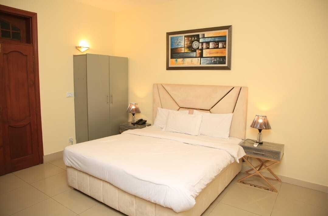 A bedroom with a bed, nightstands, a wardrobe, and a wall-mounted artwork.