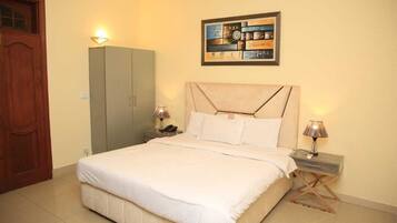A bedroom with a bed, nightstands, a wardrobe, and a wall-mounted artwork.