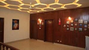 A lobby with wooden panel walls, hexagonal ceiling lights, and framed artwork. - Travel Lodge Islamabad F-8 (Islamabad)