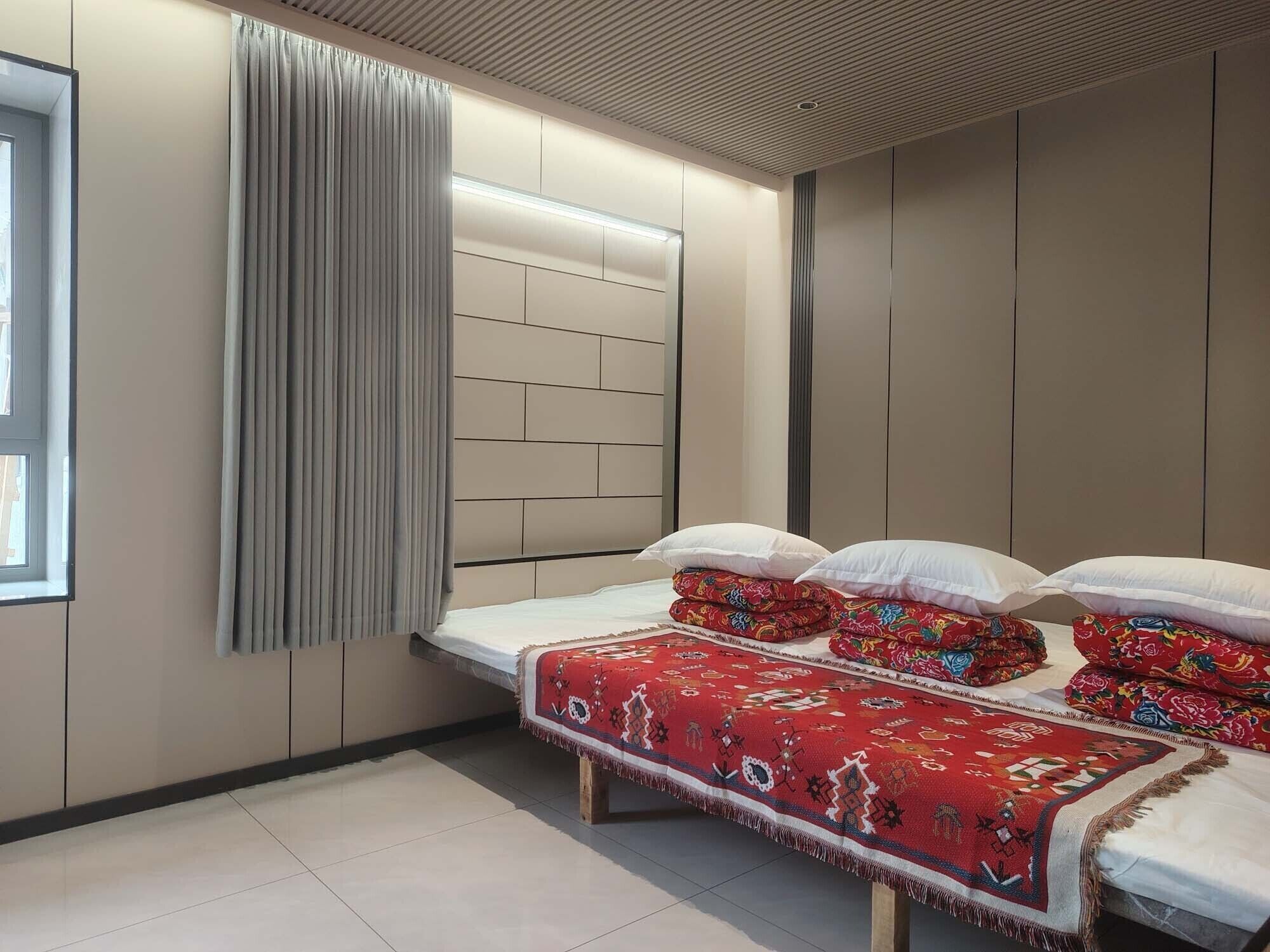 A bedroom with a bed, a window with curtains, and a headboard with built-in lighting.