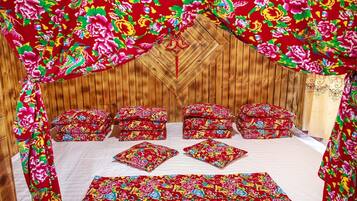 A bed with floral-patterned bedding and pillows, a wooden headboard, and a wooden wall.