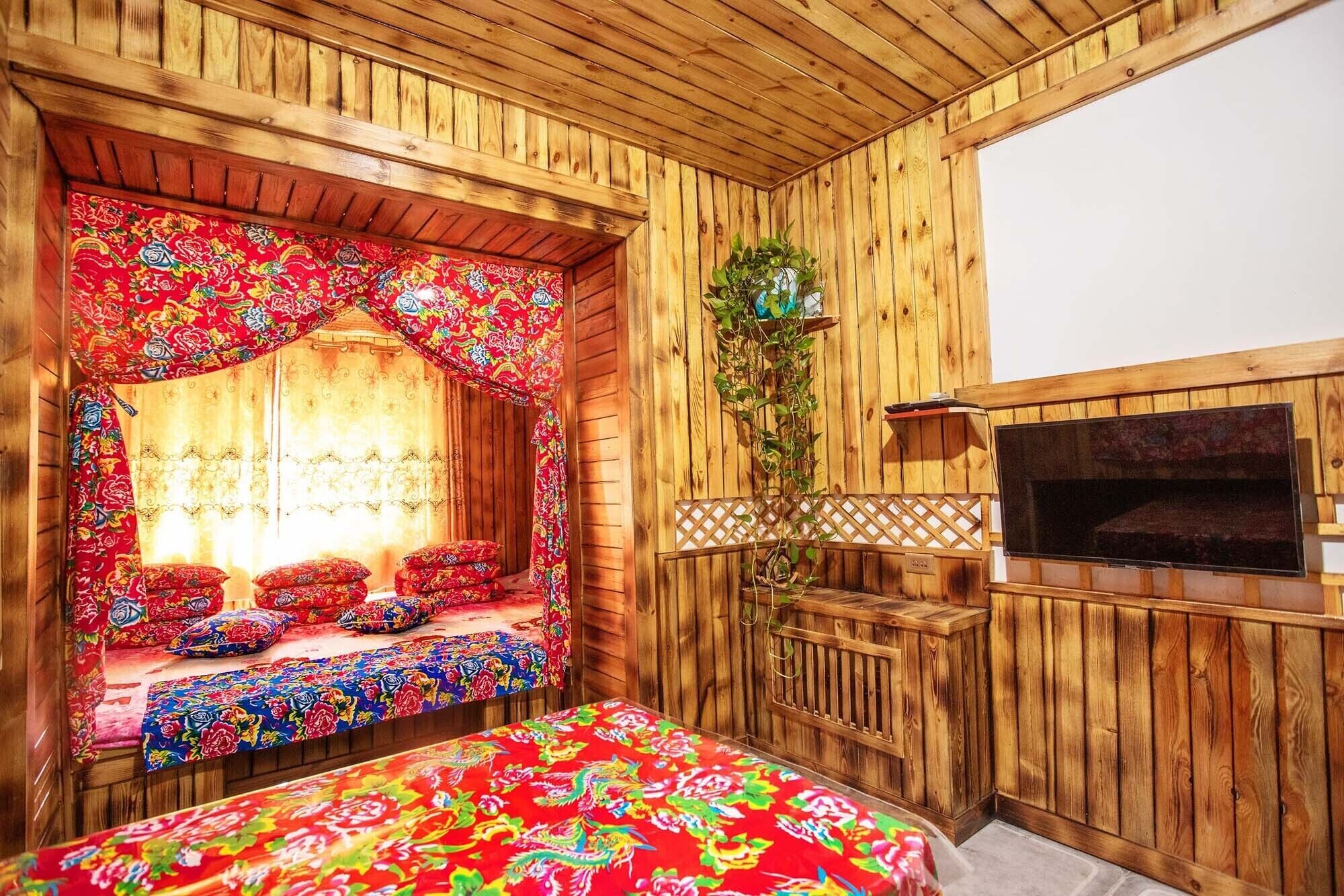 A wooden room with a bed, a bench, a TV, and a plant.