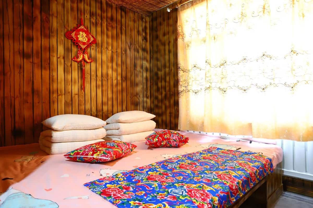Una habitación con paredes de madera, una cama con colcha estampada de flores y almohadas.
