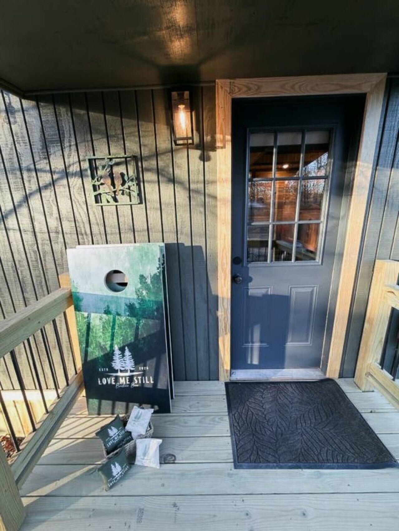 A wooden deck with a door, a welcome mat, and a poster advertising a lodge.