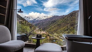 A room with a view of a valley, mountains, and a table with teapots.